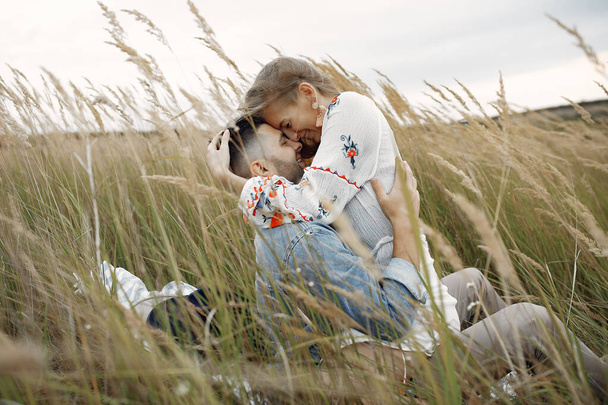 Loving couple in a wheat field. Beautiful blonde with her boyfrinds. They sitting on a blanket - Foto, Bild