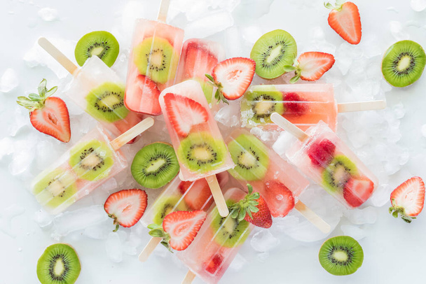 Refreshing homemade strawberry Kiwi popsicles in a pile on a bed of ice.  - Photo, Image