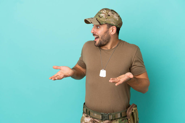 Militar com tag de cachorro sobre isolado em fundo azul com expressão facial surpresa - Foto, Imagem