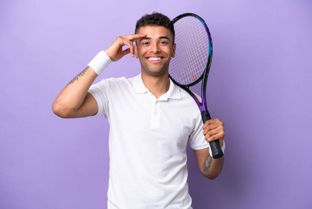 Молодой бразилец на фиолетовом фоне играет в теннис - Фото, изображение