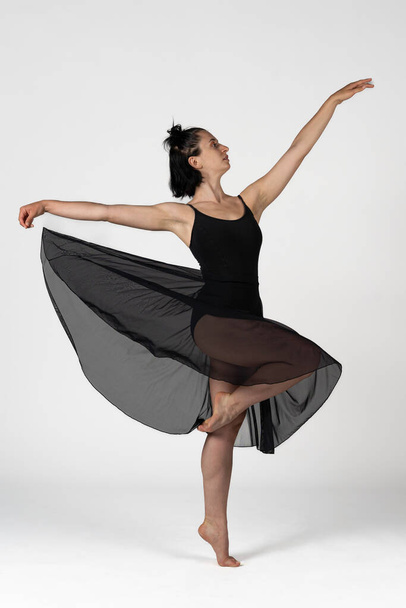 Φωτογραφία στούντιο. Στούντιο πλάνο μιας νεαρής χορεύτριας με μαύρο σώμα που χορεύει - Φωτογραφία, εικόνα