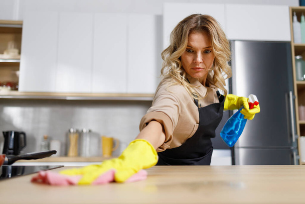 Donna in grembiule nero pulizia cucina - Foto, immagini