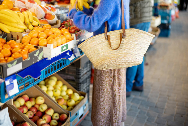 Woman shopping fruits with reusable mesh bag at local market. Cropped view with no face. Sustainability and organic local food concept - Φωτογραφία, εικόνα