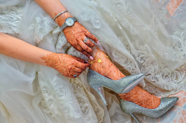 Patas femeninas con tatuaje de henna. La novia india está mostrando diseño mehndi. pies mehndi en hermosos zapatos de novia de boda femeninos con tatuajes mehndi. Tradición india - Foto, imagen