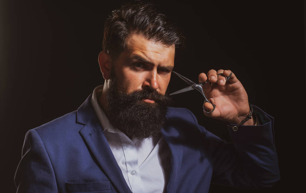 Bearded man, portrait of man with long beard and moustache. Barber scissors for barber shop. Vintage barbershop, shaving. Brutal serious male with modern hairstyle on black - Фото, изображение