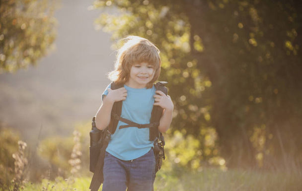 Child hiker with backpack hike in hills background. Cute boy with hiking equipment in the mountains - Photo, Image