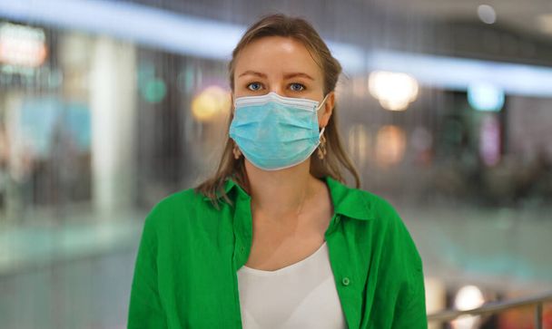 女性はモールに医療用マスクをつけている。公共の場所でマスクを着用する. - 写真・画像