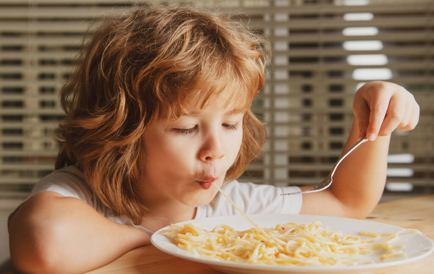 Close up head shot of child eating pasta, spaghetti. Kids face, little boy portrait - 写真・画像