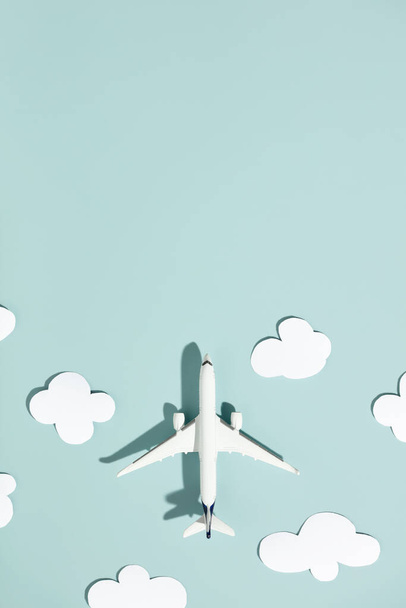 Avión de juguete en miniatura y nubes de papel sobre un fondo colorido. Viajes, vacaciones, turismo, aerolíneas, concepto de vuelos de bajo costo. Vista superior, plano. - Foto, imagen