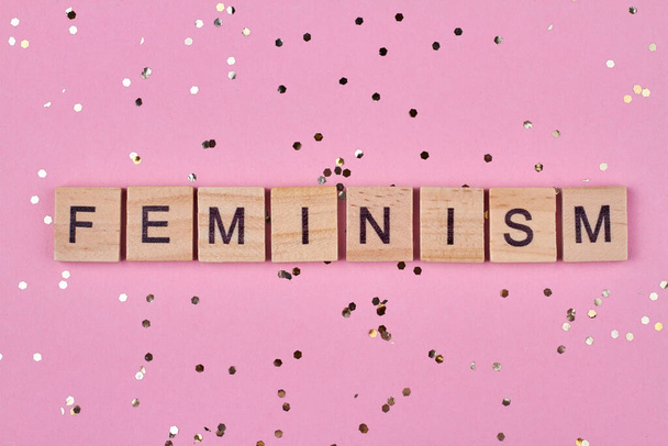 Feminism word written on wooden cubes against pink background. Flat lay. - Photo, Image