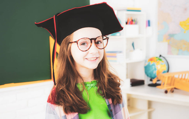 Elementary school learning and kids concept. Little student in graduation cap - Zdjęcie, obraz