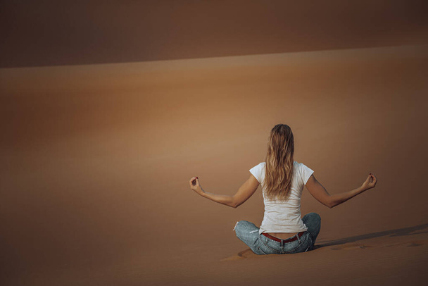 Back Side of Young Female Doing Yoga Exercises in the Desert. Meditation on Beautiful Peaceful Sandy Background. Soul Balance and Harmony Concept. - Фото, зображення