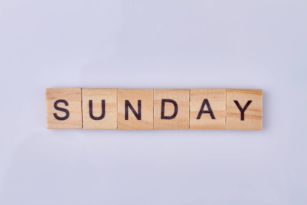 Sunday word made with wooden cubes and black letters. Isolated on white background. - 写真・画像