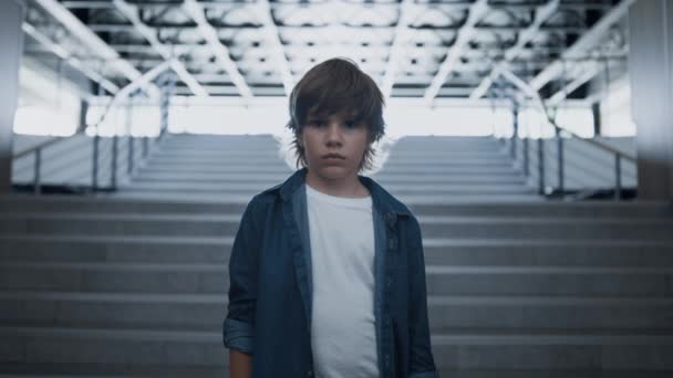 Sad boy face looking camera unhappily close up. Depressed schoolboy standing alone at empty staircase. Upset little outcast feeling despair suffer after class bullying. Loneliness in school concept. - Footage, Video