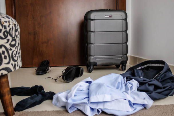 ソファの上でスーツケースを持った男が旅の準備をしてる。コンセプトは新しい家です - 写真・画像