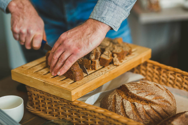 Cutting  Dark Bread Slices  On Wooden Board - Foto, imagen