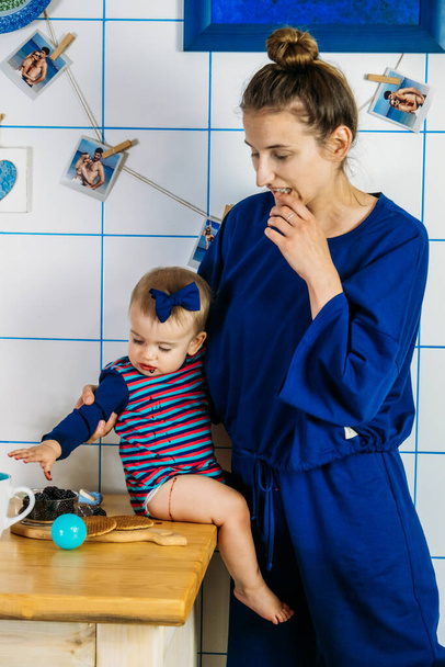 I primi frutti e bacche per i bambini. Madre e figlia bambino mangiare more in cucina a casa - Foto, immagini