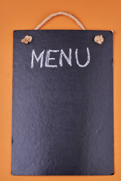 Word MENU written with chalk on black board on color background. Top view and copy space. - Photo, Image