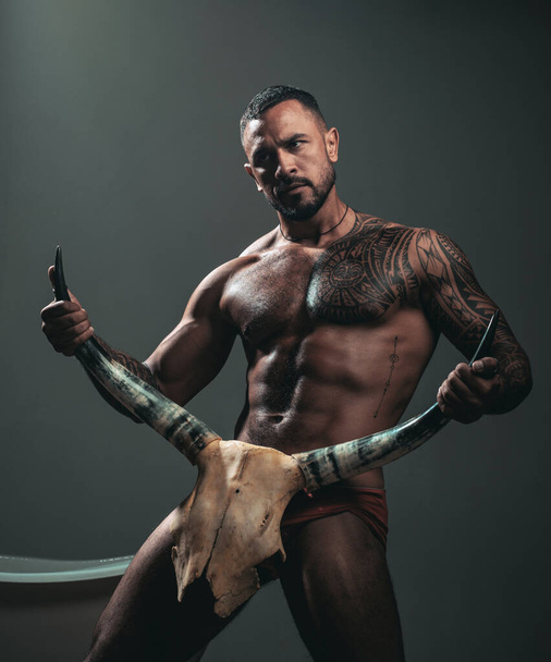 Improving male sexual performance. Sexy hispanic macho with muscular body and sexual nature holding animals skull and horns. Sexi latino man showing his sexual desire and attraction. - Фото, изображение