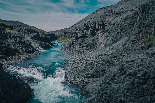 Aerial drone panorama of studlagil canyon in Iceland, picturesque valley with basalt columns standing high on a warm summer day. Closeup of the basalt tiwers in the water - Photo, Image