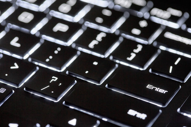 Verlicht computertoetsenbord. Moderne technologische zwart-wit achtergrond. Close-up van verlicht toetsenbord met selectieve focus. - Foto, afbeelding