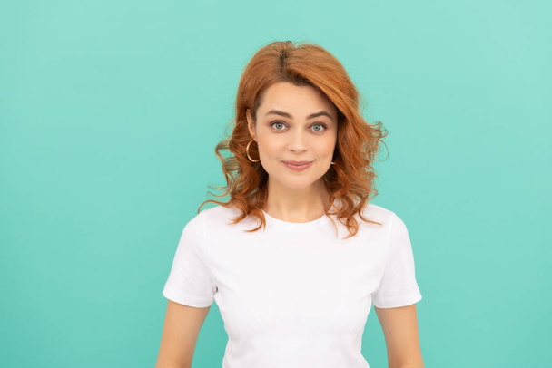 cheerful redhead woman with curly hair on blue background. - Foto, Imagen