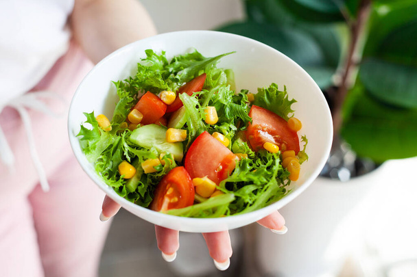 Bir kâse yeşil sağlıklı eko salata, elinde hafif mutfaktaki kadın. - Fotoğraf, Görsel