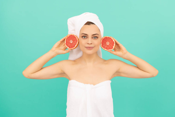 νεαρή κοπέλα σε πετσέτα μετά το ντους με φρούτα σε μπλε φόντο. - Φωτογραφία, εικόνα