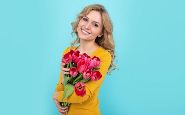 happy girl with spring tulip bouquet on blue background. - 写真・画像