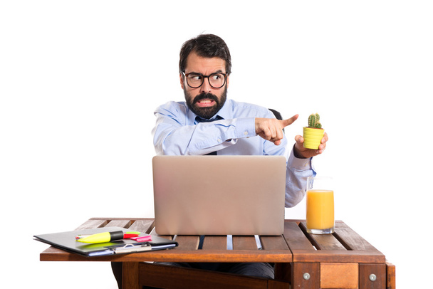 Бизнесмен в своем офисе держит кактус
 - Фото, изображение