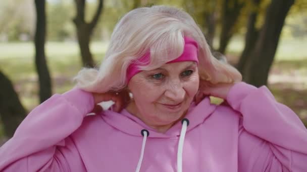 Ritratto di atletica anziana corridore sportivo allenamento donna, ascoltare musica in cuffia, indossare cappuccio - Filmati, video