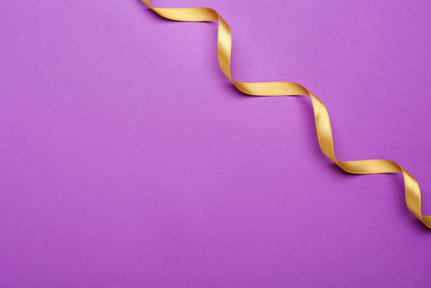 Beautiful golden ribbon on purple background, top view. Space for text - Fotó, kép