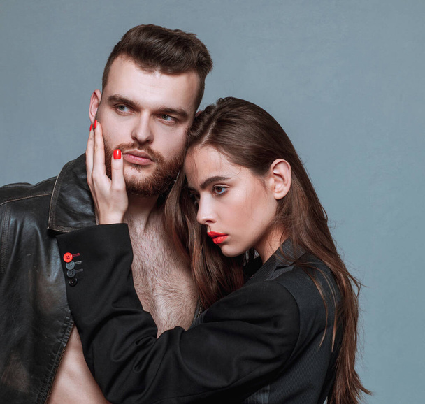 She adores male brutal beard. Girlfriend passionate red lips and man leather jacket. Passionate hug. Couple passionate people in love. Man brutal well groomed macho and attractive girl cuddling. - Фото, зображення