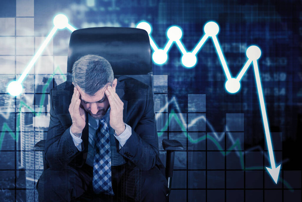 Stressed businessman sitting near declining finance graph with cityscape background - Foto, Imagen