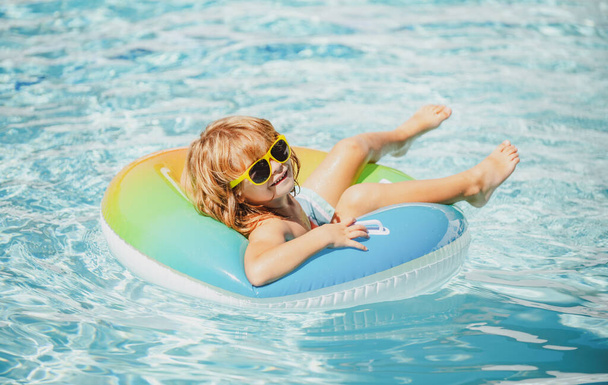 Summer vacation. Summertime kids weekend. Boy in swiming pool. Funny boy on inflatable rubber circle - Fotó, kép