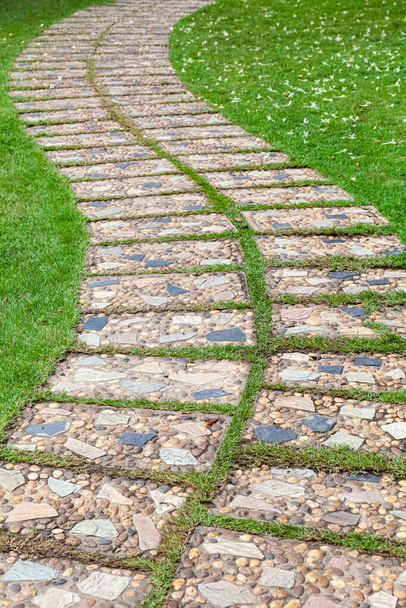 Brązowe granitowe płyty chodnikowe wzorzyste w zielonych trawnikach w ogrodzie - Zdjęcie, obraz