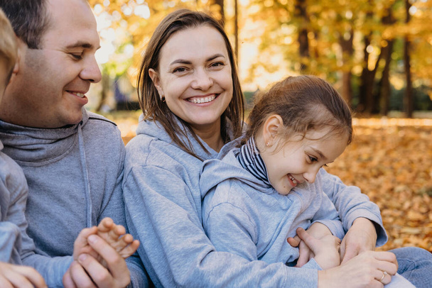 Portrait of a lovely family of four having good time outdoors in the autumn park. Parents with two children. Happy family leisure. Smiling happy child. - Photo, Image