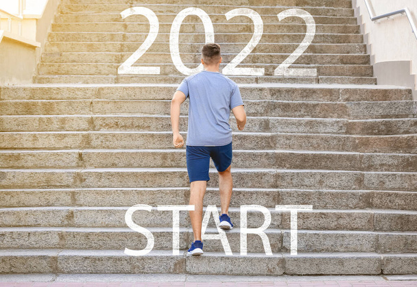 Sporty young man running up the stairs outdoors. Concept of 2022 goals - Valokuva, kuva