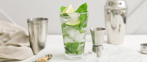 Glass of fresh mojito and bartender supplies on white table - Photo, Image