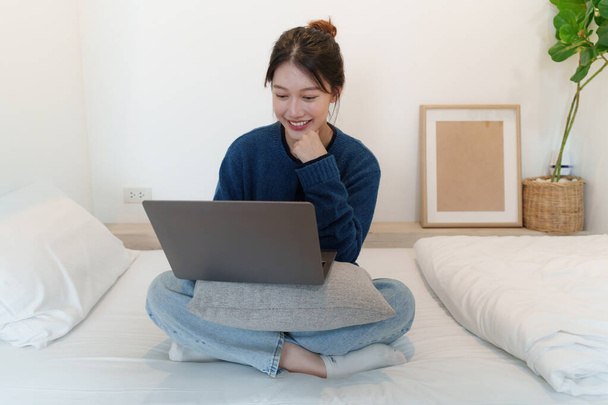Sosyal medyayı dizüstü bilgisayarla kullanan Asyalı bir kadının portresi. Yaşam tarzı, online alışveriş, yatakta rahatlamak. - Fotoğraf, Görsel