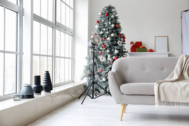 Christmas tree, sofa and lighting equipment in modern photo studio - Zdjęcie, obraz