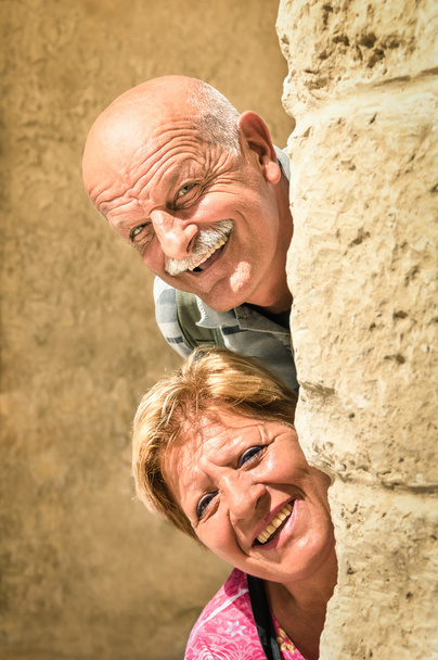 Ευτυχισμένο ζευγάρι ανώτερος ερωτευμένος κατά τη συνταξιοδότηση - χαρούμενη ηλικιωμένοι τρόπο ζωής με τον άνδρα και γυναίκα με αστεία παιχνιδιάρικο στάση - που επισκέπτονται την παλιά πόλη κατά την περιήγηση στα αξιοθέατα - Φωτογραφία, εικόνα