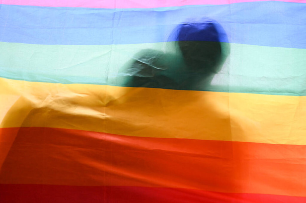 Eşcinsel çiftlerin sarılıp yattığı gökkuşağı bayrağı. Gay gururu, Biseksüel, Transseksüel, Homoseksüel, LGBT aşk sembolü. - Fotoğraf, Görsel