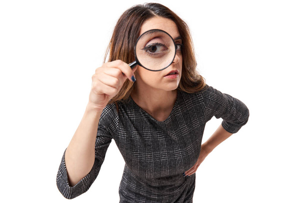 Closeup of a businesswoman looking at camera through a magnifier - Foto, Imagen