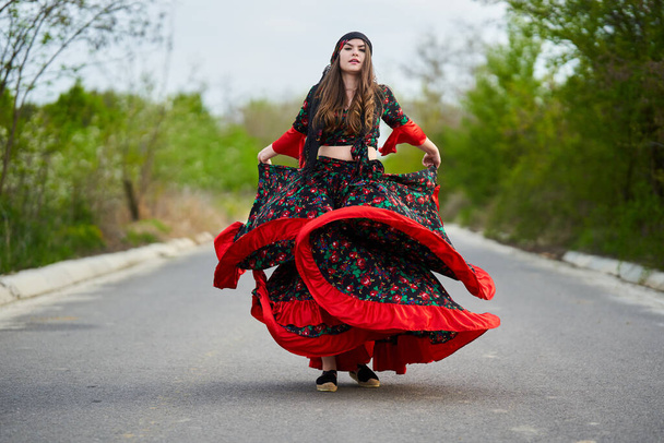 Young beautiful gypsy woman dancing in the middle of the street, in traditional costume - Foto, Imagem