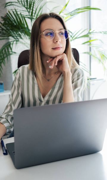 Young woman working on a computer in her office - Foto, imagen