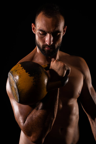 Retrato de chico guapo y en topless entrenando mientras se centra en el ejercicio de la mancuerna - Foto, imagen
