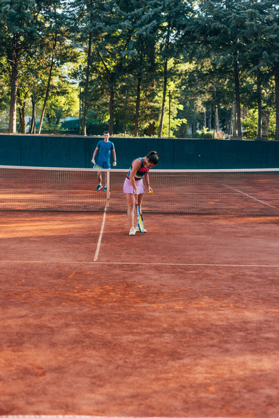 Una joven jugadora de tenis sirviendo en una cancha de barro - Foto, imagen