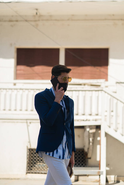 Urban businessman is having a great conversation on the phone with his mask on - Photo, Image