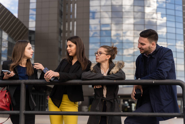 Gruppe junger Geschäftsleute spricht draußen im Stehen miteinander - Foto, Bild